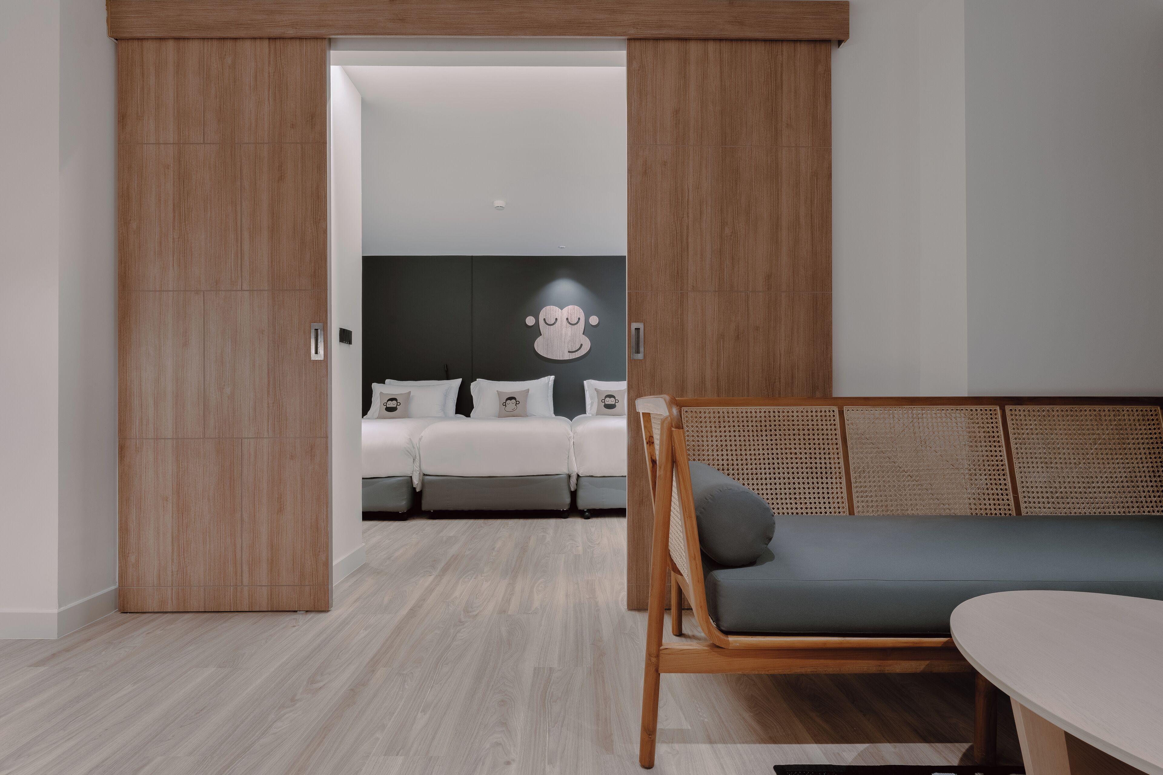 Une chambre moderne avec une armoire en bois, un canapé gris et un lit avec une literie blanche.