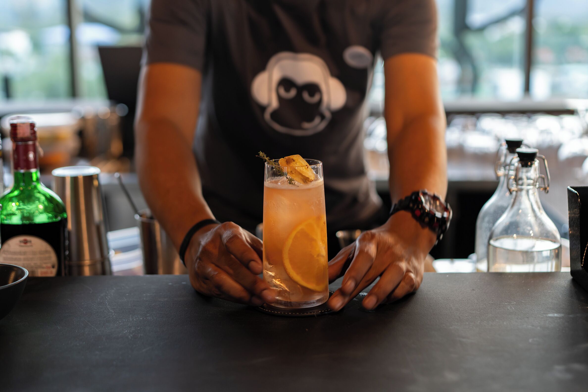 En bartender holder et højt glas med citruspynt.