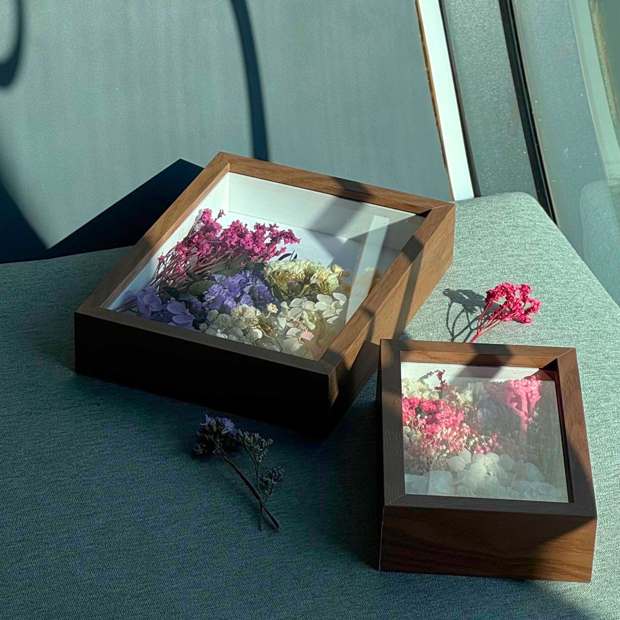 Dos vitrinas de madera con tapas de cristal, cada una con flores secas.