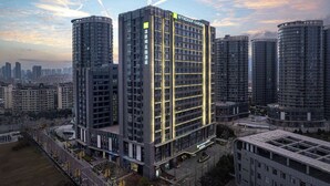 Un hôtel moderne de grande hauteur, reconnaissable à son imposante enseigne « Wyndham Garden », doté d’un atrium central et de nombreux balcons.