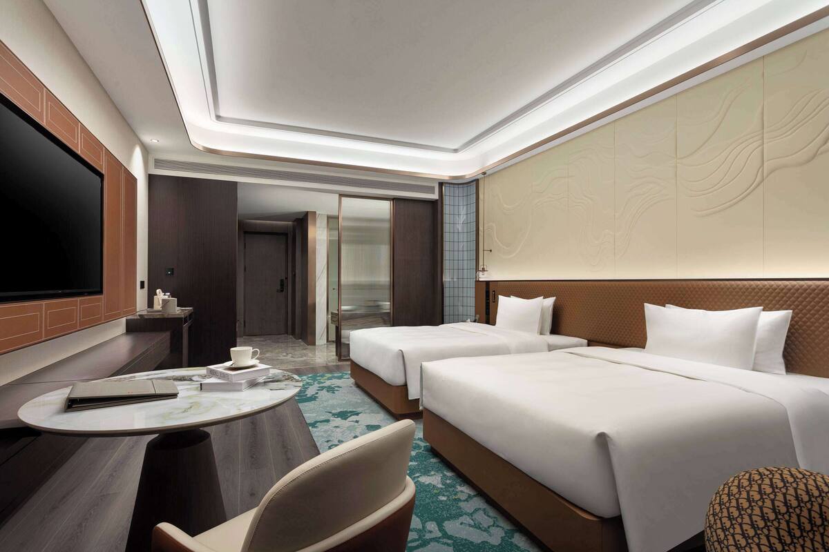 Une chambre d’hôtel avec deux lits, une télévision, un bureau et une chaise.