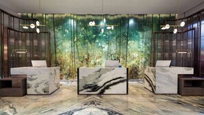 Un espace d’accueil doté de comptoirs de réception en marbre, d’un grand écran numérique et d’un décor représentant une forêt verdoyante.