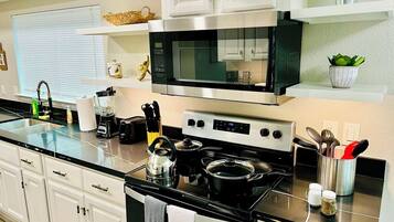 A modern kitchen with stainless steel appliances, white cabinetry, and a black countertop.