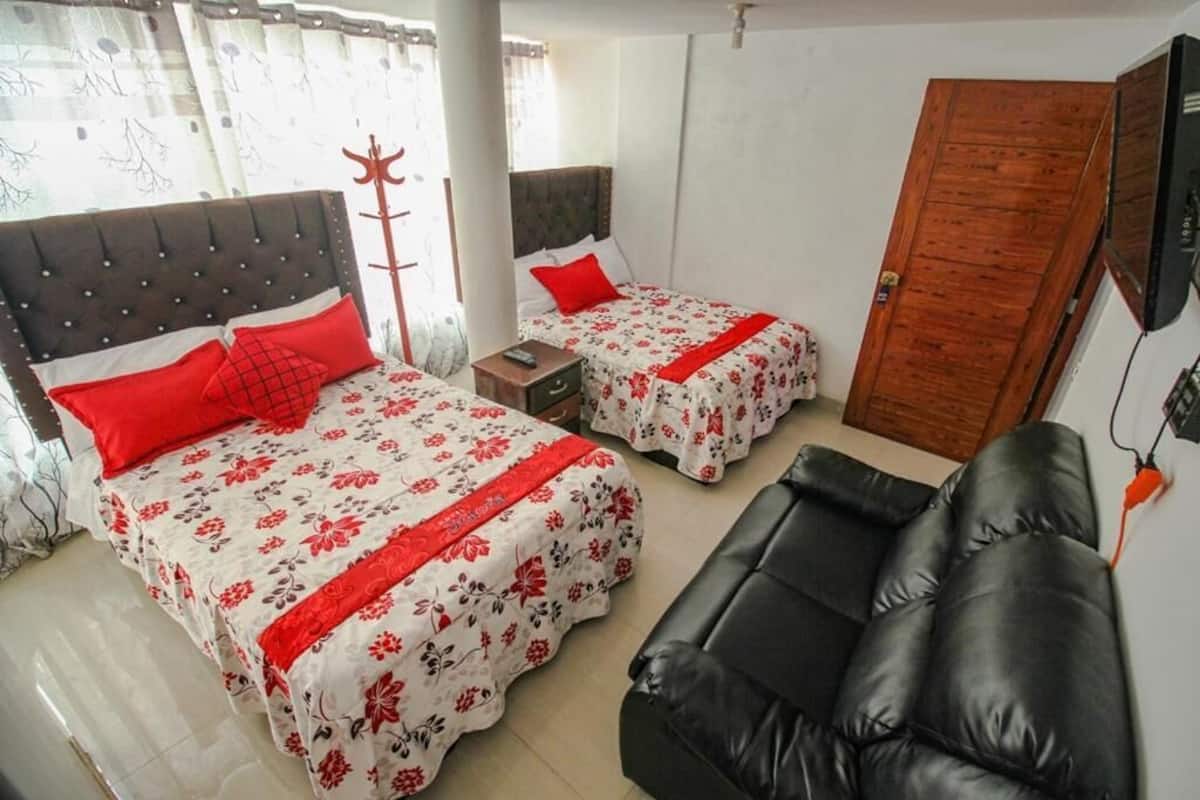 A room with two beds, a black leather sofa, and a wooden door.