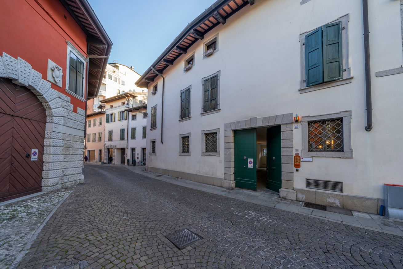 A cobblestone street with buildings featuring traditional architecture, including a red door and a green entrance.