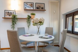 Une table de salle à manger ronde, entourée de quatre chaises, un vase rempli de fleurs et des tableaux encadrés accrochés au mur.