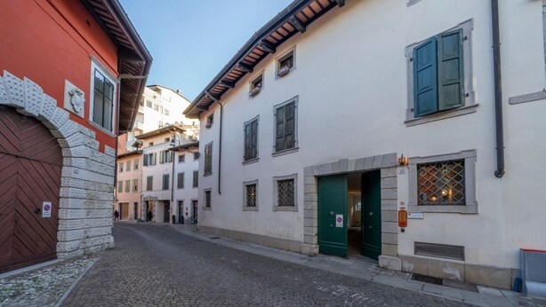 Uma rua de paralelepípedos com edifícios com arquitetura tradicional, incluindo uma porta vermelha e uma entrada verde.