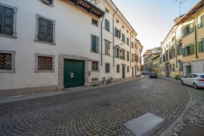 Une rue pavée bordée d’immeubles, une porte verte et une voiture garée.