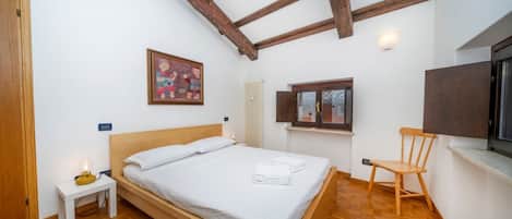 A bedroom with a wooden bed, a nightstand, a chair, a window, and a painting on the wall.