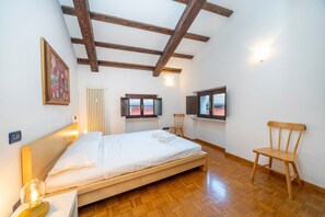Une chambre à coucher avec un lit en bois, une chaise, un radiateur et deux téléviseurs fixés au mur.