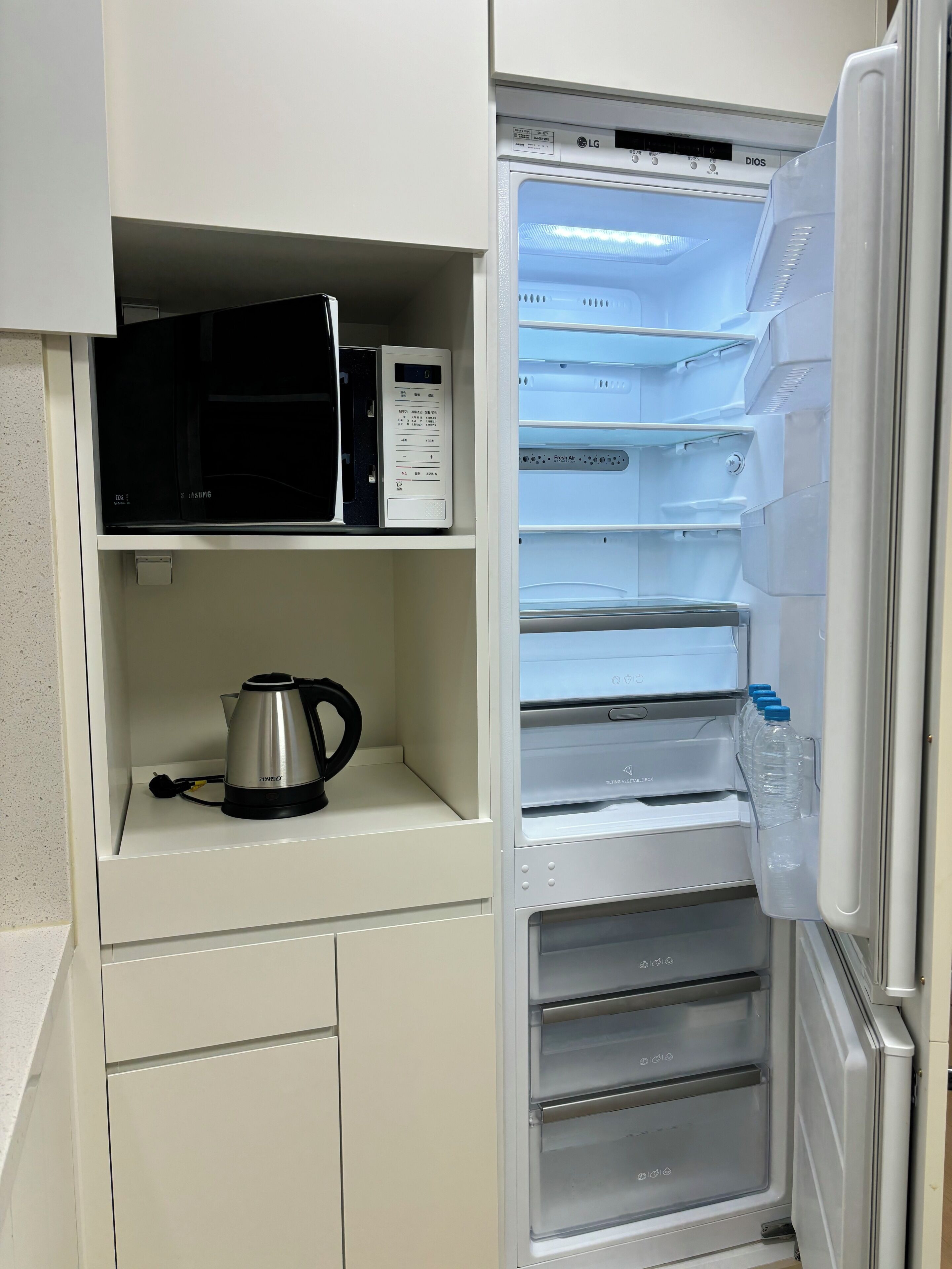 A kitchen with a microwave, kettle, and a water dispenser.