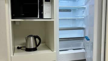 A kitchen with a microwave, kettle, and a water dispenser.
