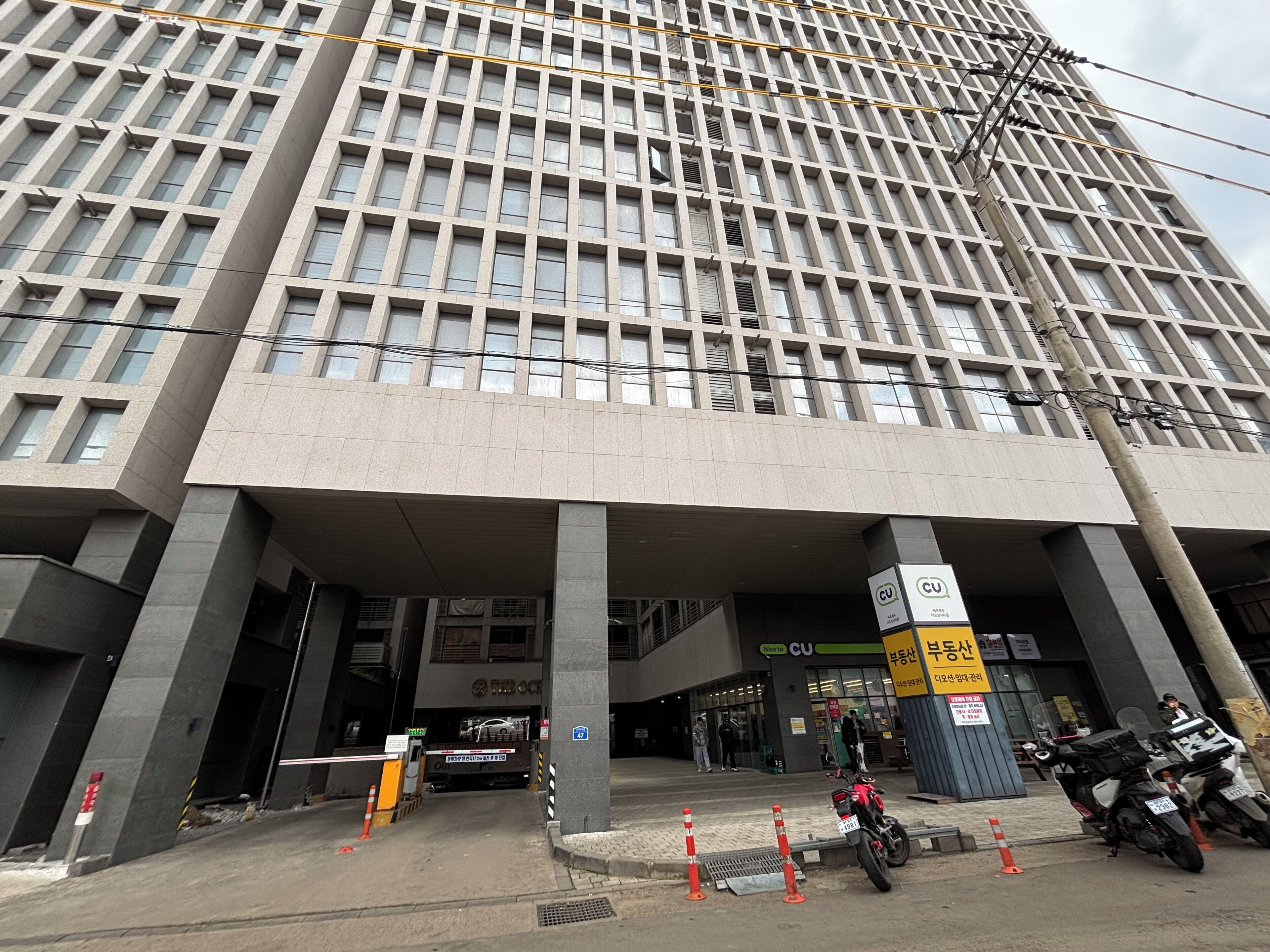 A modern building with a grid-like facade, multiple entry points, and a covered entrance area.