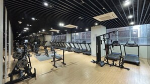Une salle de sport équipée de tapis de course, d’appareils de musculation et dotée d’une grande fenêtre.