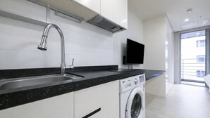 Une cuisine moderne équipée d’un lave-linge intégré, d’un grand évier et d’un téléviseur à écran plat.