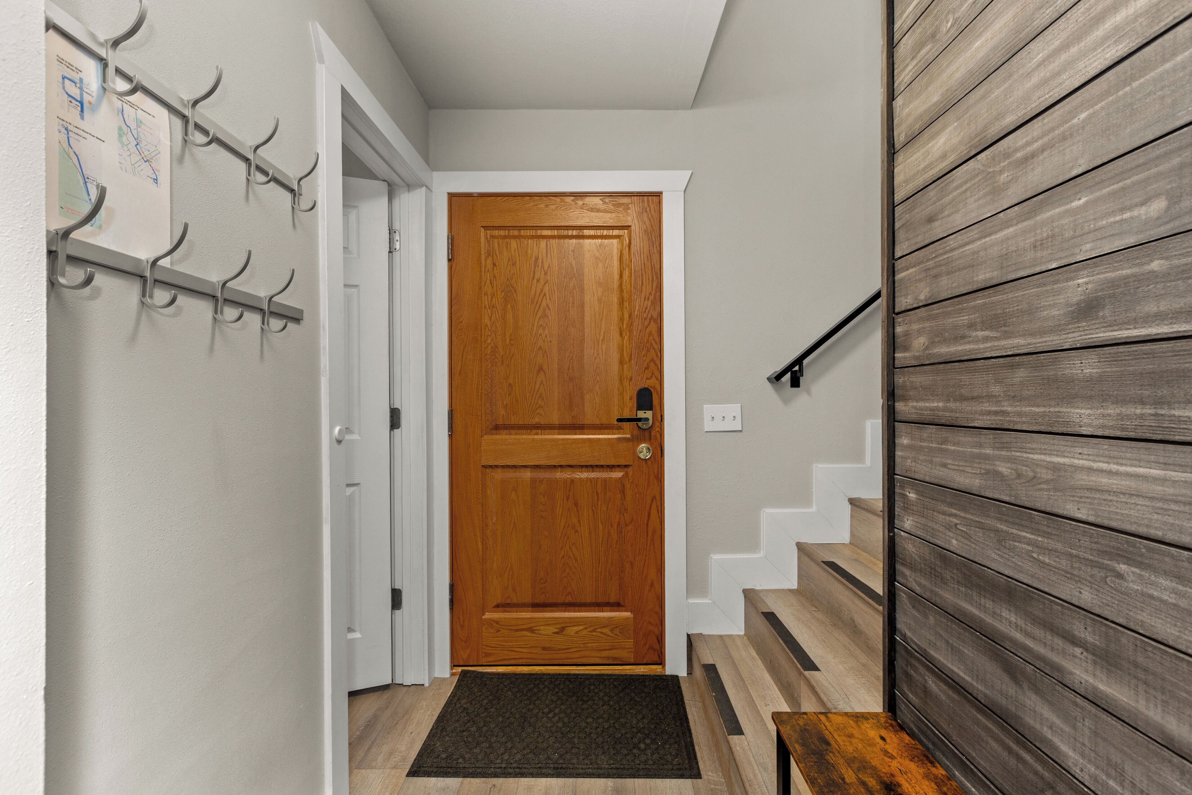 A wooden door with a doorknob, a coat rack with hooks, and a staircase with wooden steps.