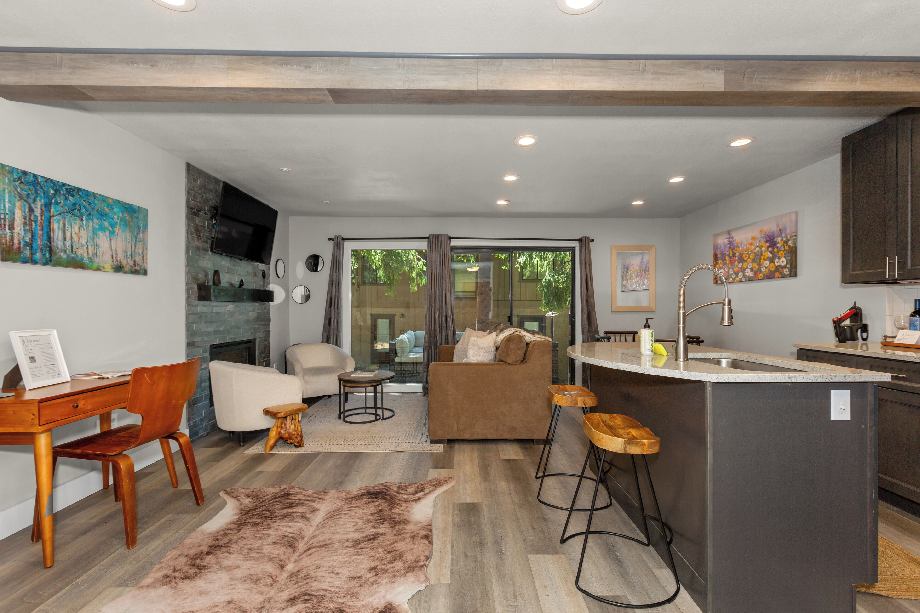 A modern kitchen with a central island, bar stools, and a dining area with a wooden table and chairs.