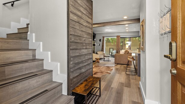 A modern interior with a wooden staircase, a bench, and a kitchen area with bar stools. - Stylish Sun Valley 2BR - Dog-Friendly - 2 Min Walk to Town (Ketchum)