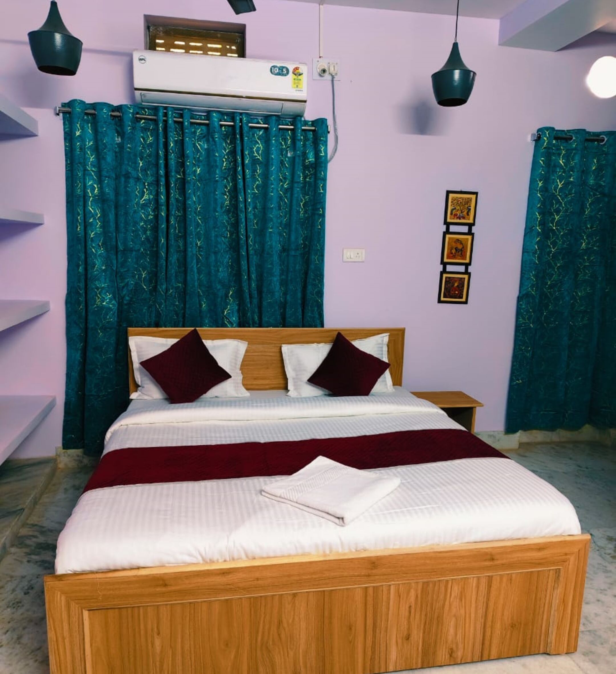 A bedroom with a wooden bed, teal curtains, and a ceiling-mounted air conditioner.