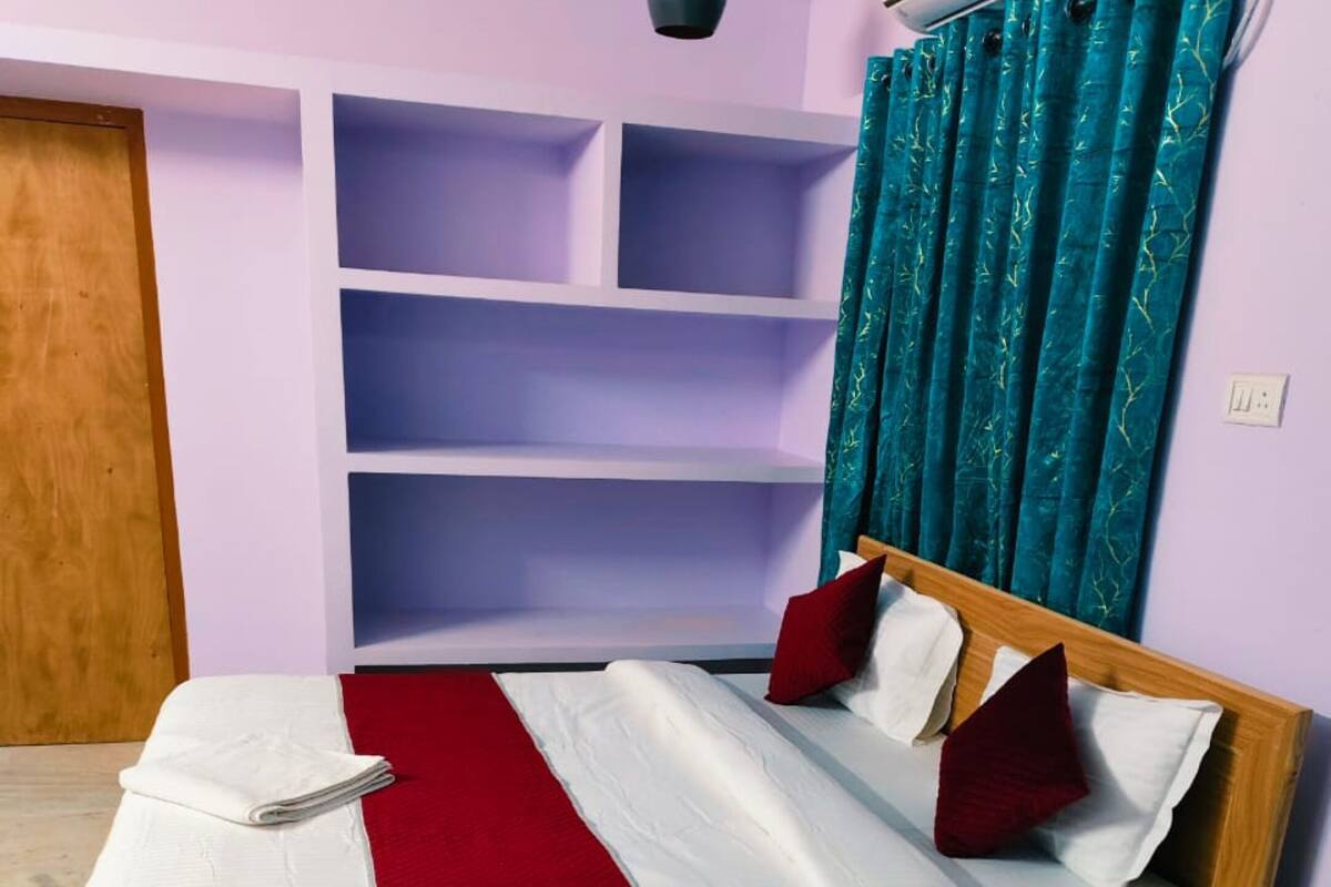 A neatly made bed with a wooden frame, white and red bedding, and a matching bedside table.