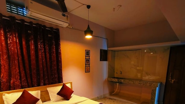 A hotel room with a large bed, a bedside table, a remote control, and a bathroom visible through an open door. - Goroomgo Rail View Guest House Puri (Puri)