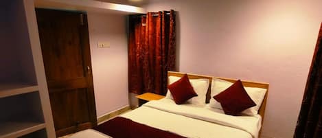 A bedroom with a bed, a wooden wardrobe, a small table, and a ceiling fan.