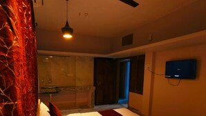 A hotel room with a bed, a TV mounted on the wall, and a ceiling fan. - Goroomgo Rail View Guest House Puri (Puri)