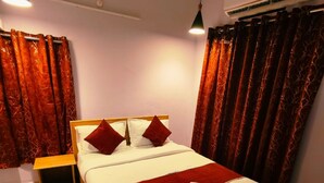 A neatly made bed with a wooden headboard, red and white bedding, and a small bedside table. - Goroomgo Rail View Guest House Puri (Puri)