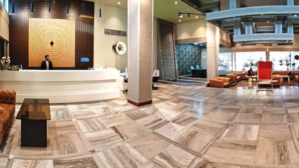 A spacious lobby with a reception desk, seating area, and a large window providing a view of the outside.