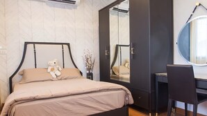 A bedroom with a bed, a desk, a chair, a mirror, and a teddy bear. - The Loft Living Space (Samut Prakan)