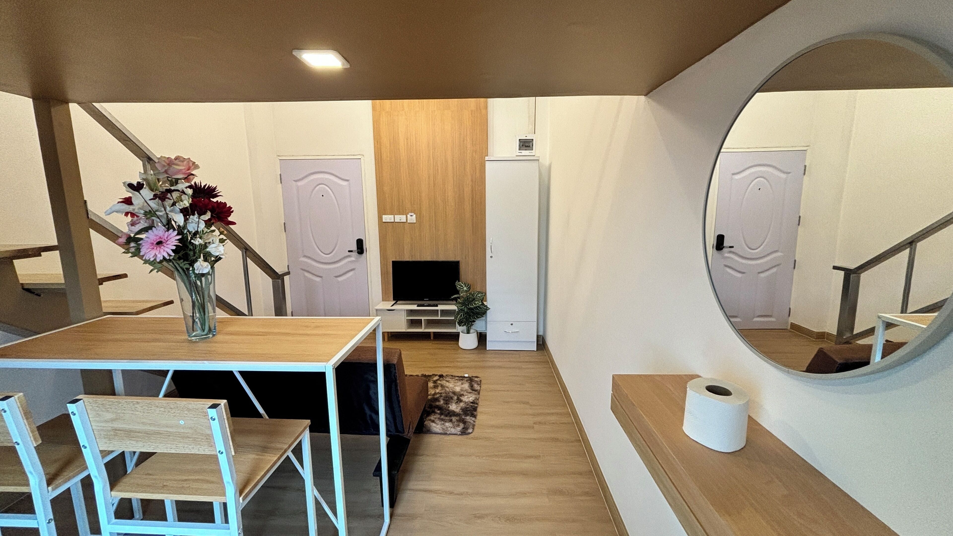Un interior moderno con una mesa de madera, sillas, un televisor y un espejo.