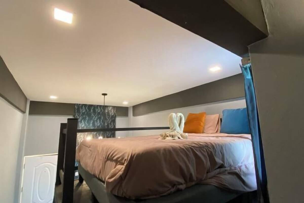 A bunk bed with a headboard, a bedside table, and a wall-mounted light fixture.