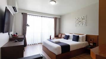 A hotel room with a bed, a desk, a television, and a window with curtains.