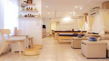 A modern living room with a sofa, a dining table, and a pool table. There are pet bowls on the floor and a shelf with bottles.