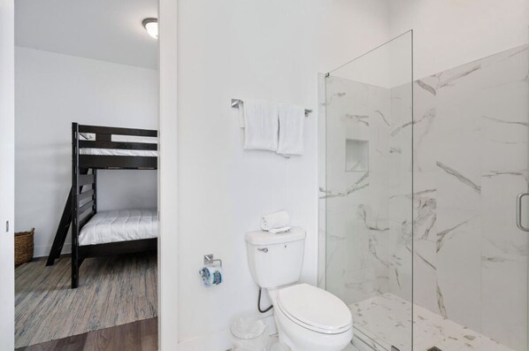 Ein Zimmer mit einem Etagenbett, einer Toilette und einer Dusche mit Marmorwänden.