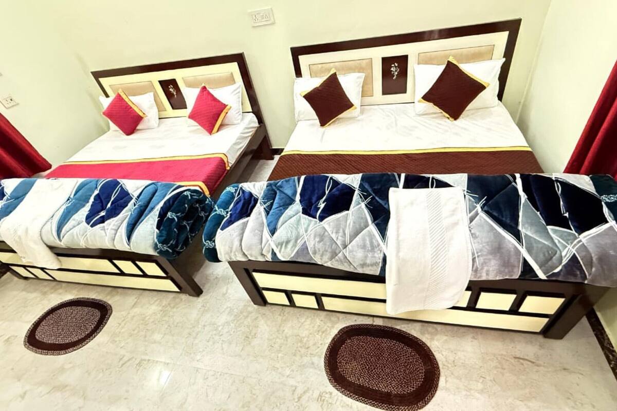 Two double beds with headboards, red curtains, and a patterned bedspread.