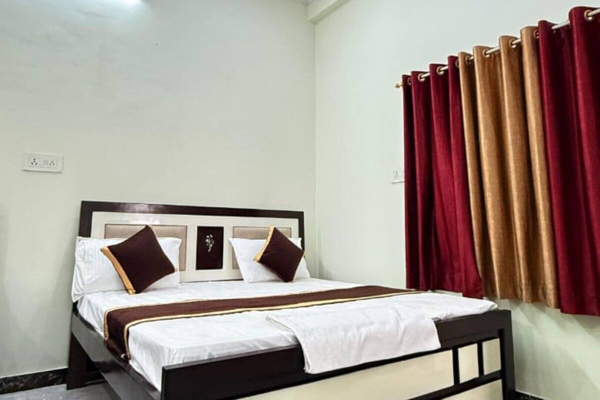 A hotel room with a bed, a ceiling light, and a window with curtains.