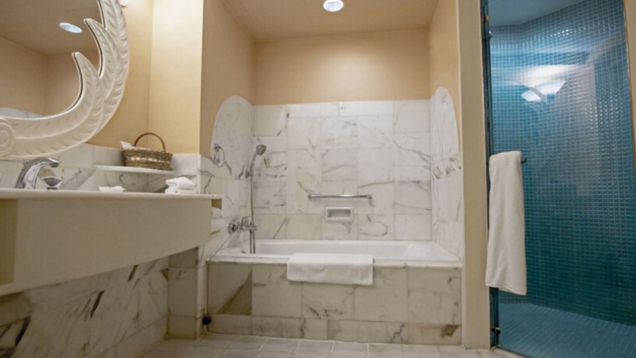 Un baño con bañera, lavamanos con espejo y zona de ducha.