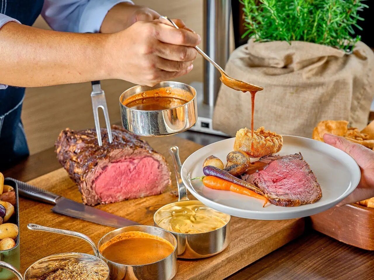 Una persona sirviendo un plato de bistec con verduras y salsa.
