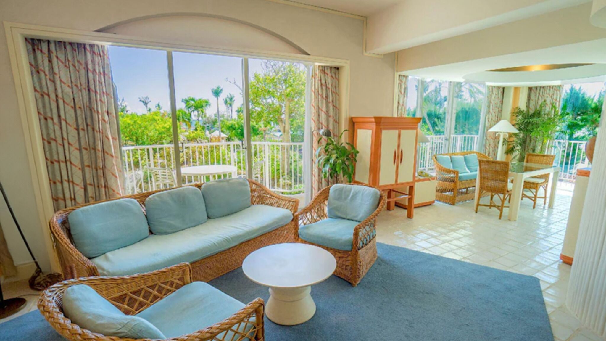 A room with a sofa, chairs, a table, and a view of the outdoors.
