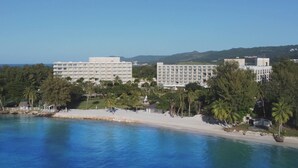 Un hotel frente al mar con varias edificaciones, una playa y una vista despejada.
