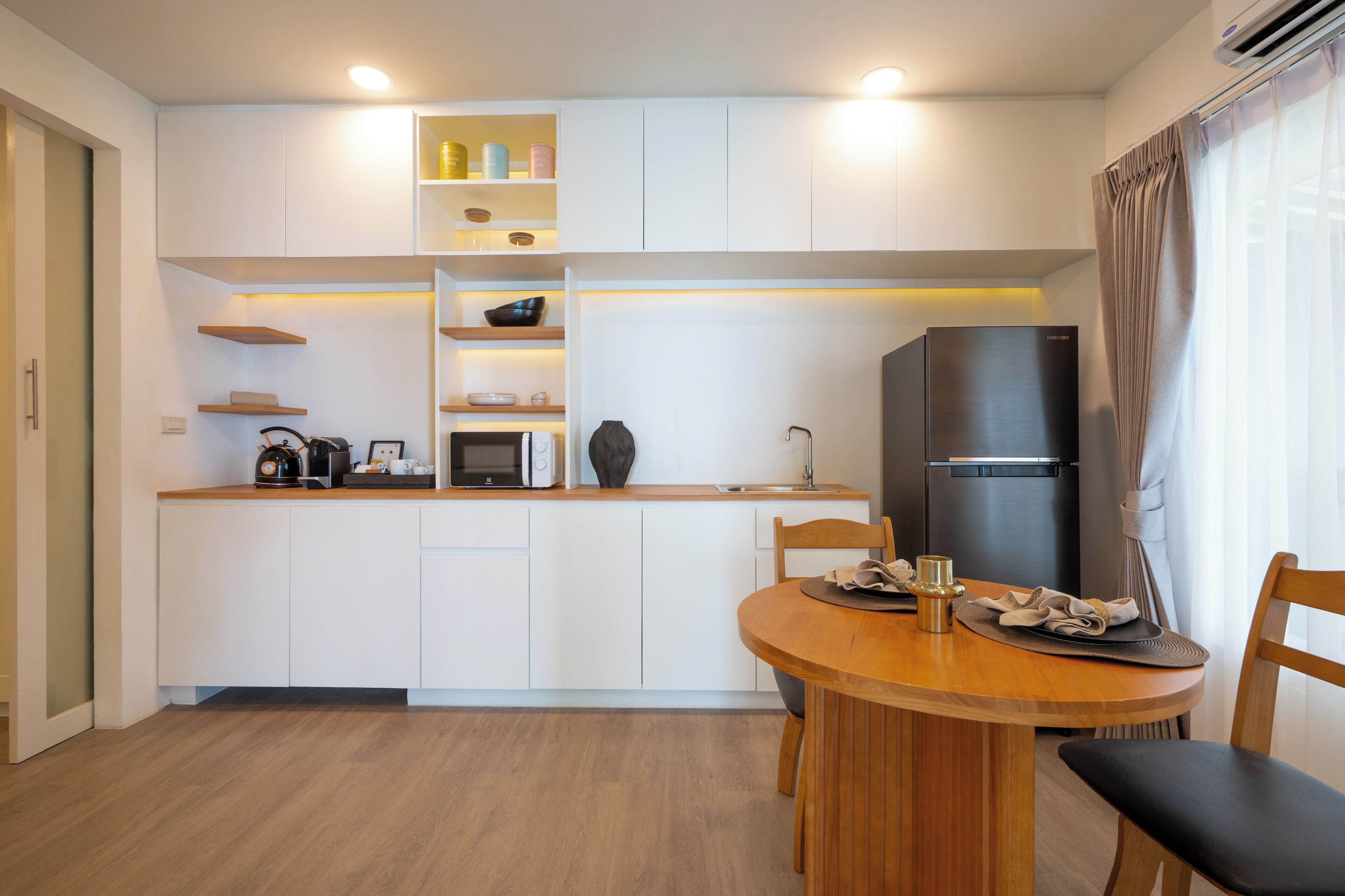 A modern kitchen with white cabinets, a black refrigerator, and wooden countertops.