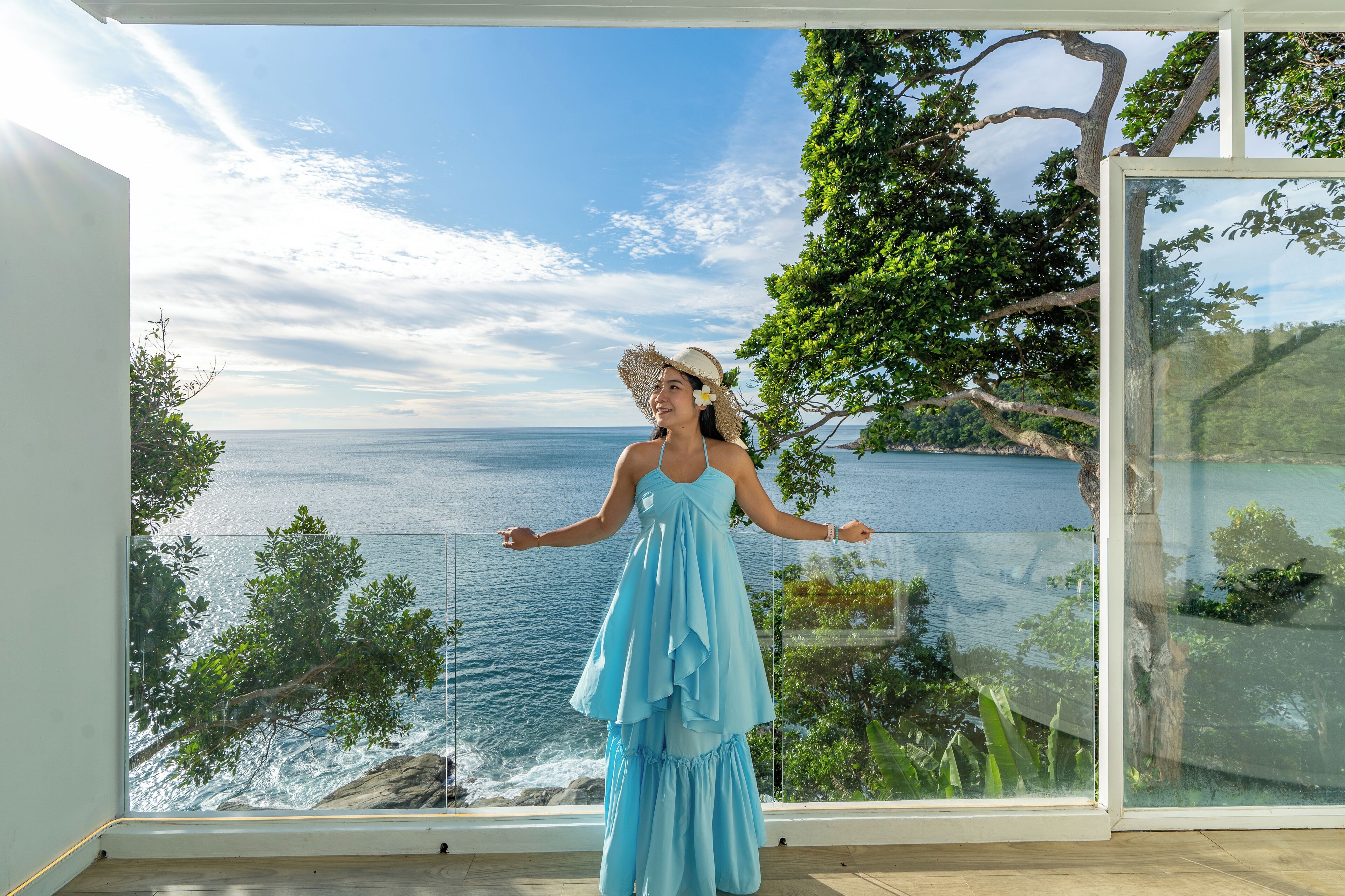 A room with a large glass window overlooking a scenic ocean view.