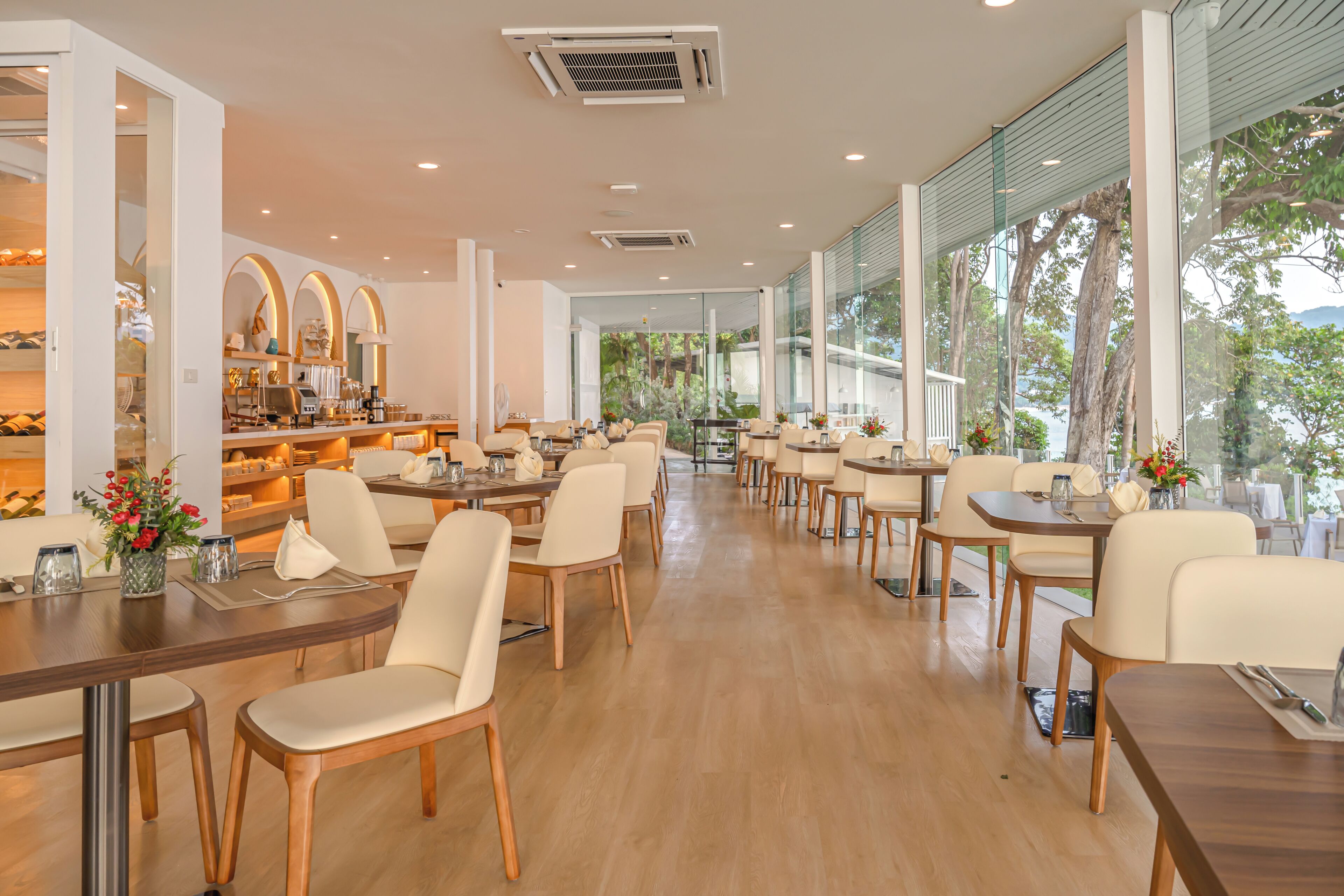 A spacious restaurant with high ceilings, large windows, and a long counter with chairs.