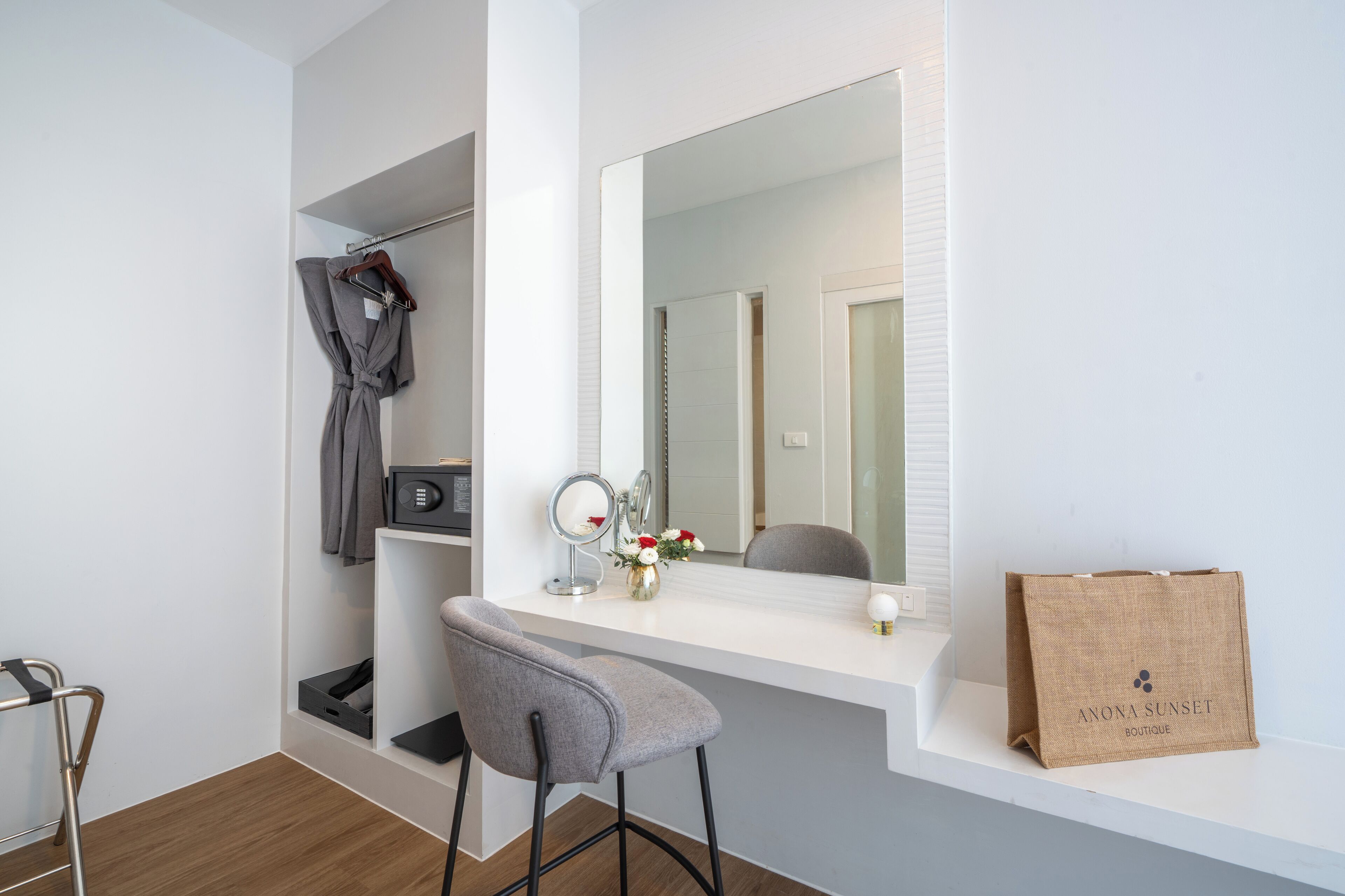 A modern bathroom with a vanity, mirror, robe, and a bag on the counter.