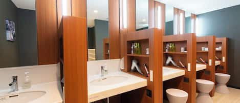 A modern bathroom with multiple sinks, wooden vanity units, and individual toilets.