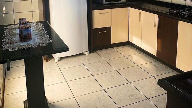 A compact kitchen with a refrigerator, microwave, and a small dining table. - Regina Houses Sua Casa na Terra das Cataratas (Foz do Iguaçu)