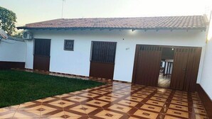 A building with a tiled patio and a door leading to an interior space. - Regina Houses Sua Casa na Terra das Cataratas (Foz do Iguaçu)