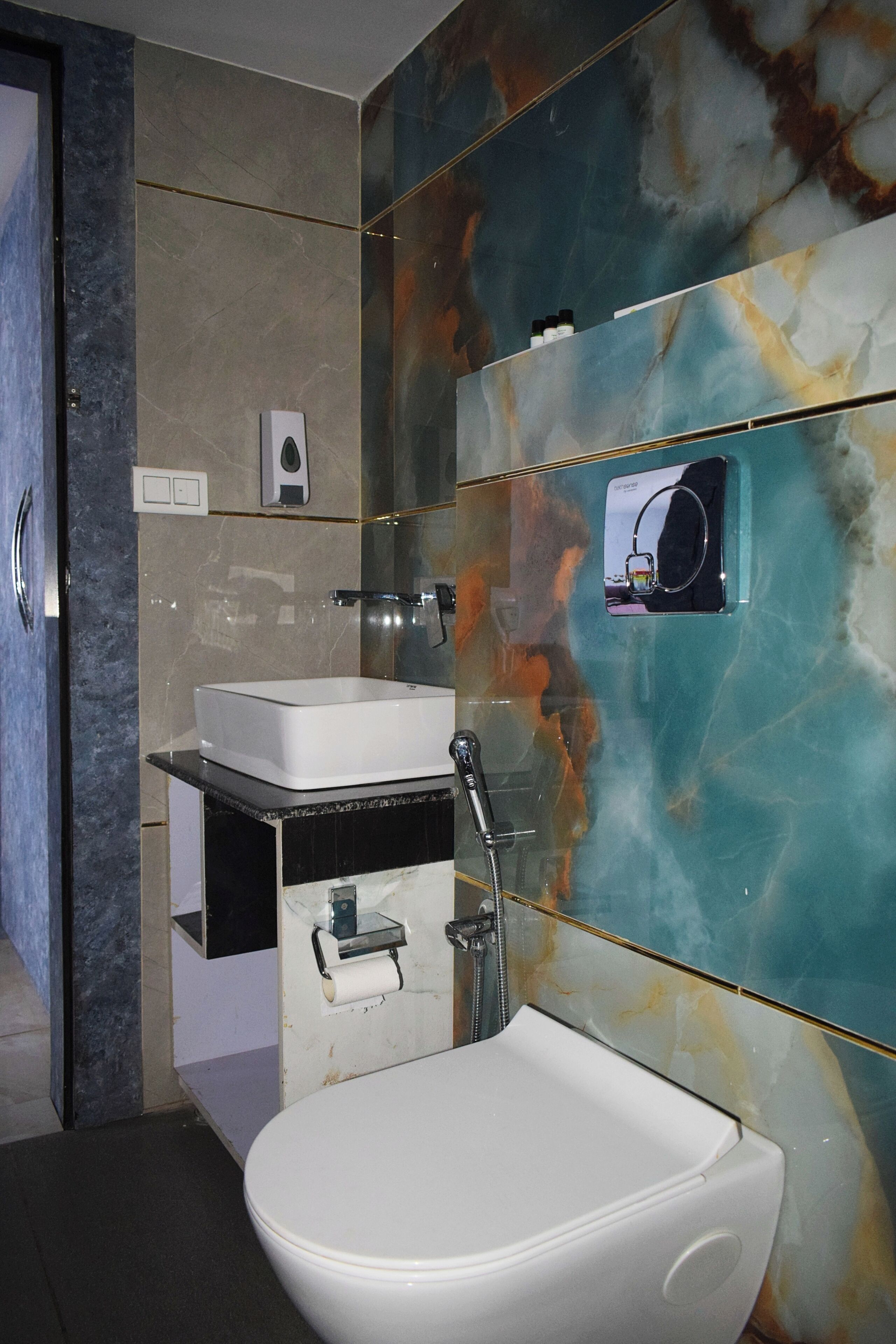A bathroom with a white sink, a handheld showerhead, and a glass-enclosed mirror.