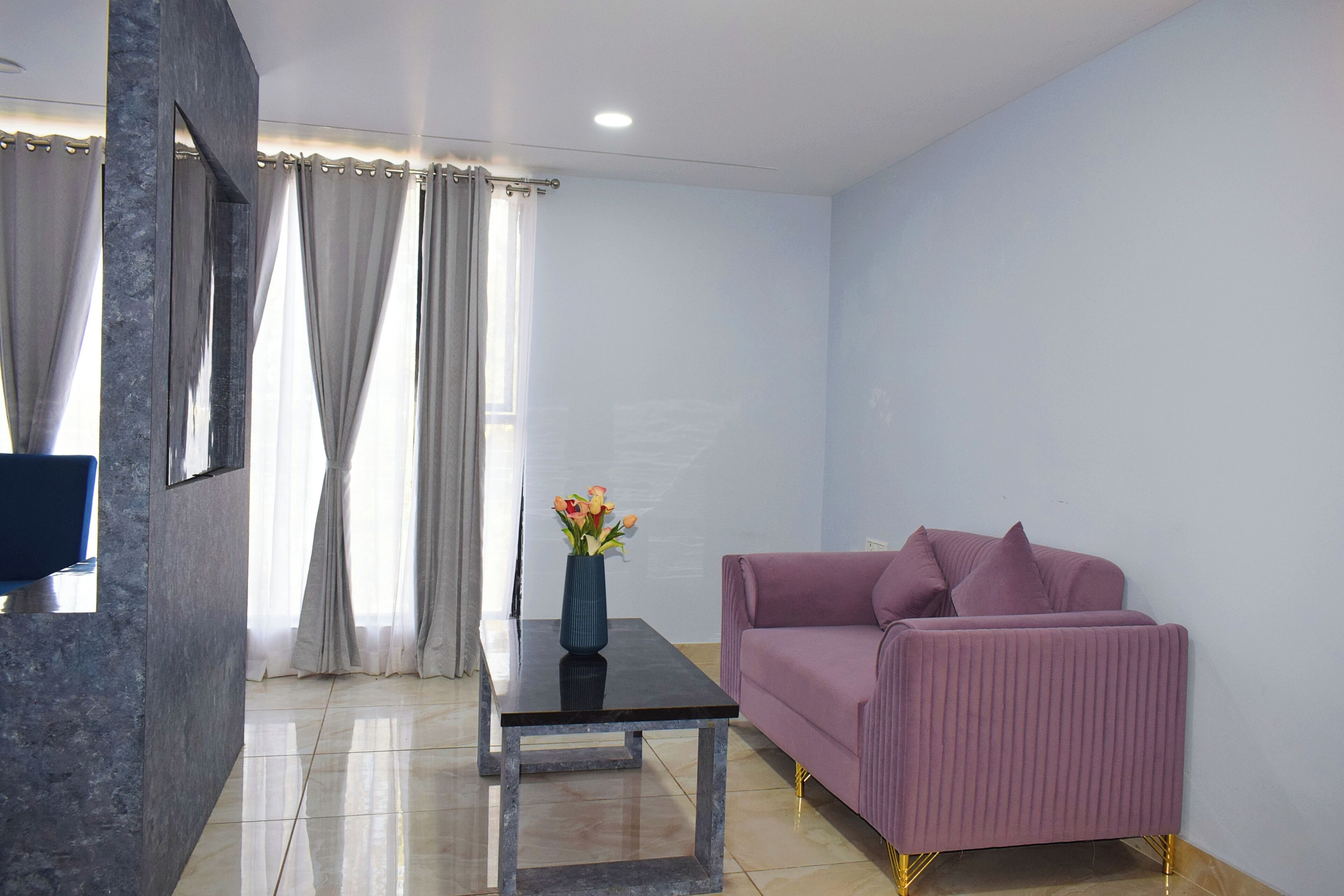 A modern living room with a sofa, a coffee table, and a vase with flowers.